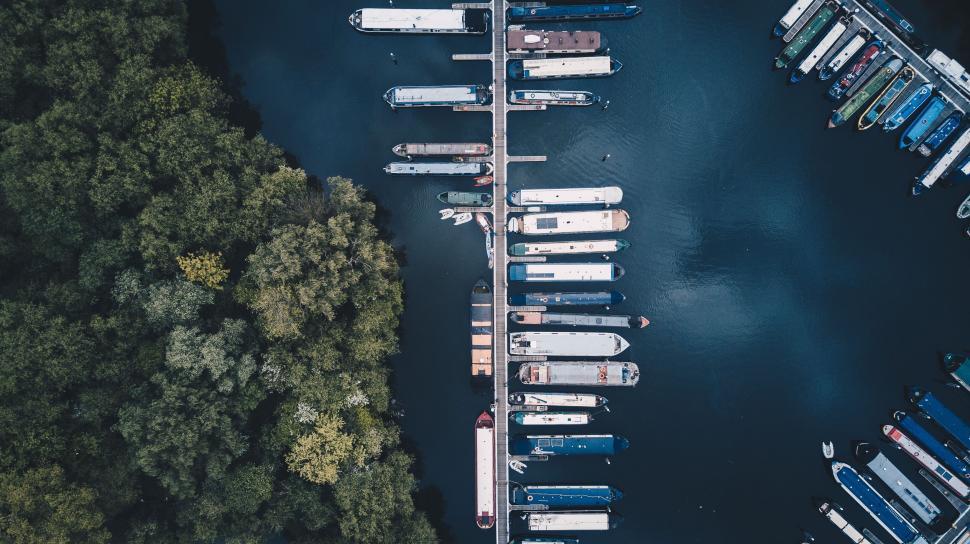 Free Image of Aerial view of boats docked along pier next to forest 