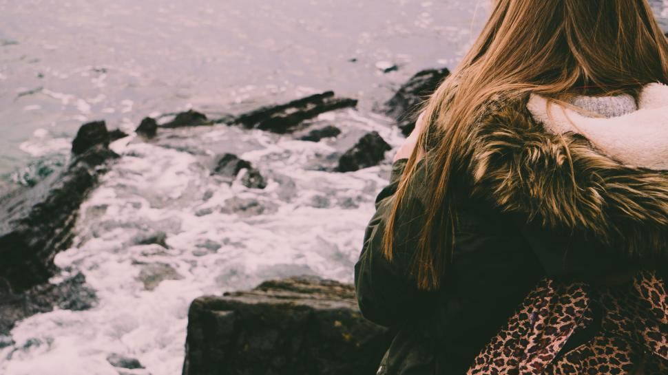 Free Image of Person in winter clothing near rocky seashore. 
