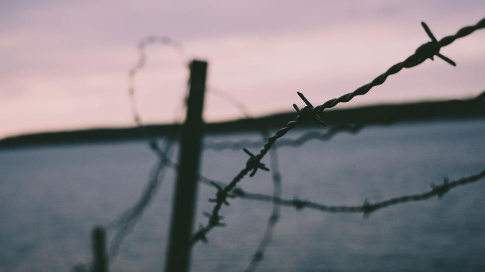 Free Image of Twilight photo featuring barbed wire fence near water 