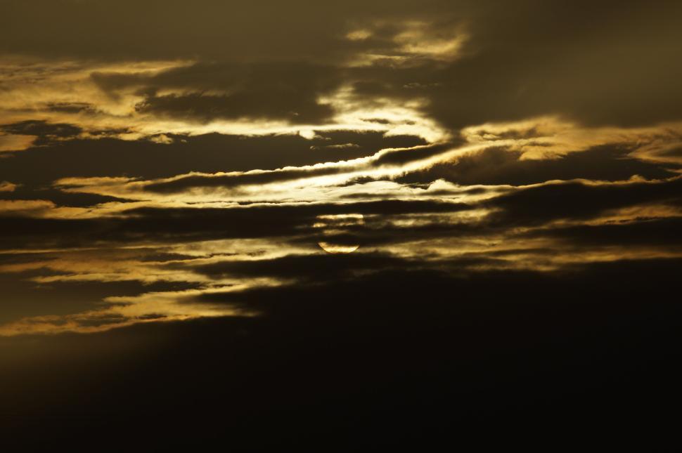Free Image of Dramatic clouds obscuring a golden sunset in the sky 