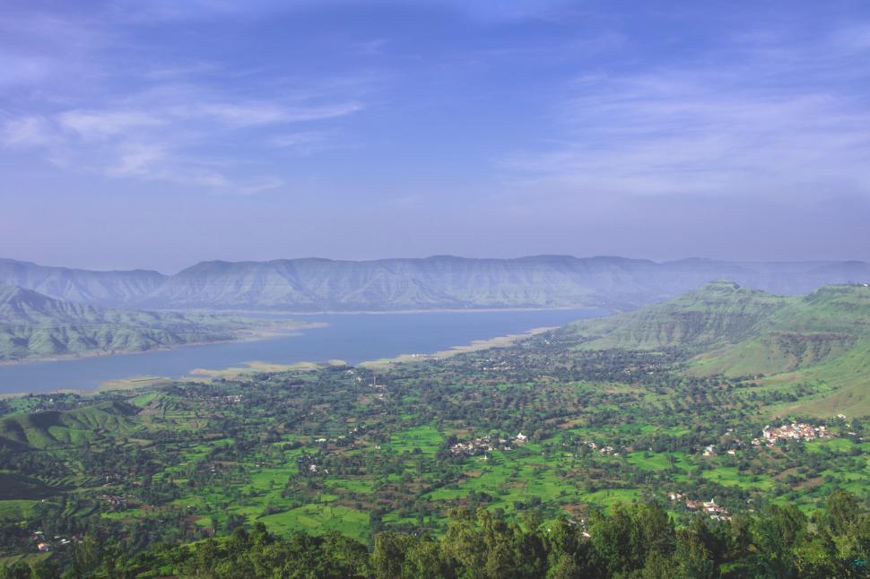 Free Image of Panoramic view of lush green valley under blue sky 
