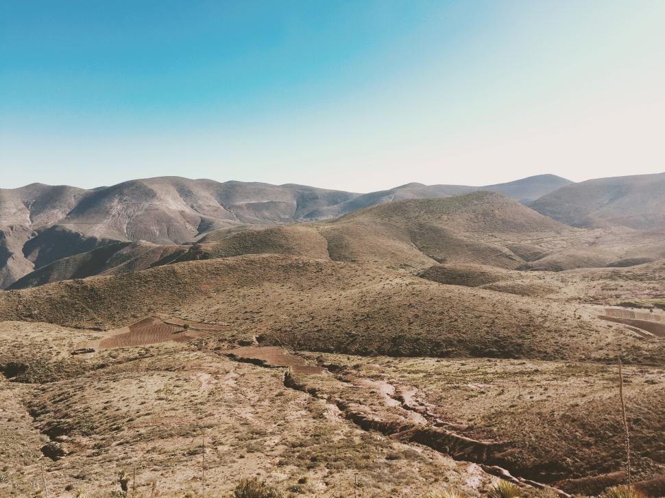 Free Image of A vast arid landscape with rolling hills under blue sky. 