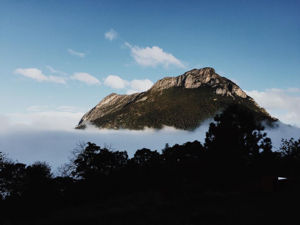 Free Image of A majestic mountain peak rising above the cloud line. 