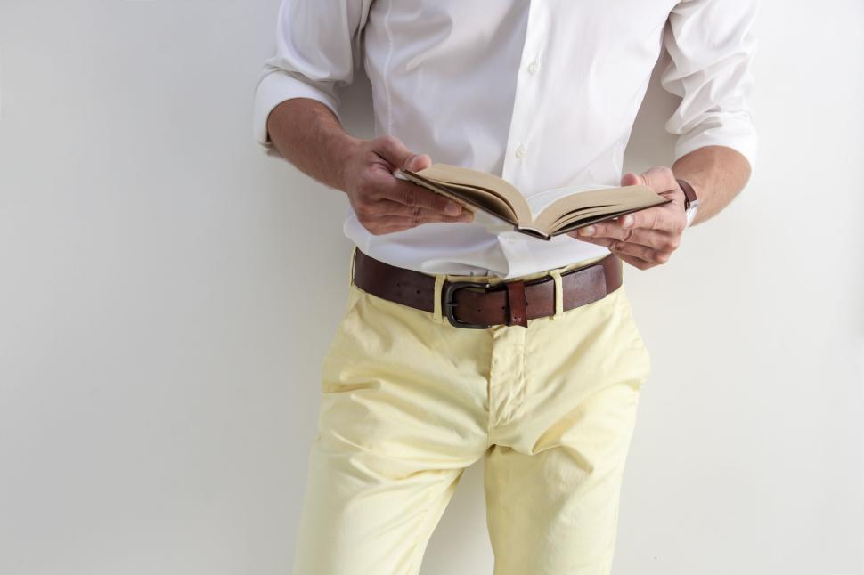 Free Image of Man holding an open book wearing yellow pants. 