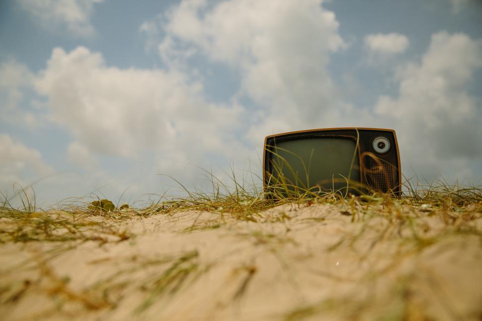 Free Image of Old television abandoned on sandy beach under sky 