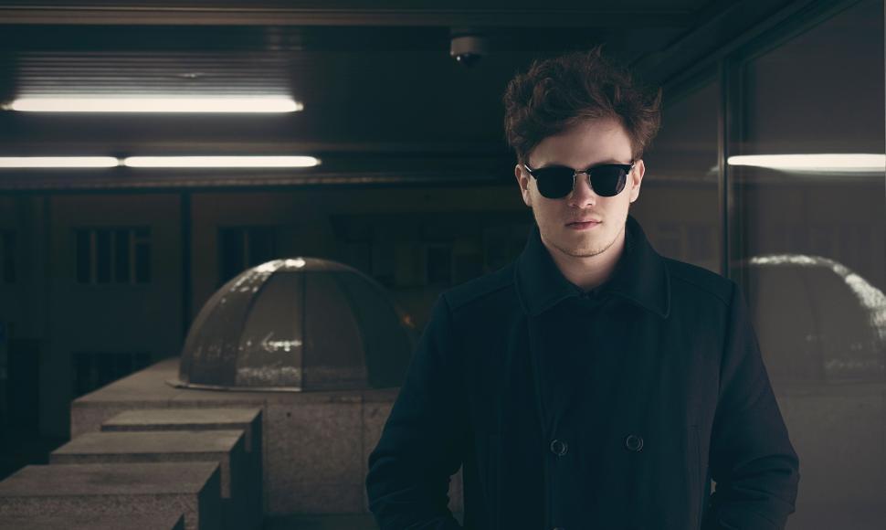Free Image of Man in dark coat and sunglasses under artificial lighting. 