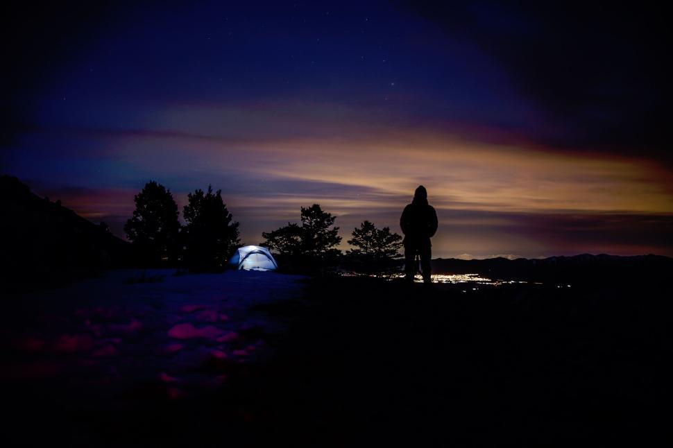 Free Image of Nighttime silhouette of camper under illuminated sky 