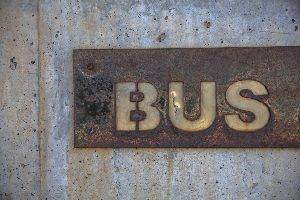 Free Image of Rusty sign with the word  BUS  on a concrete wall 