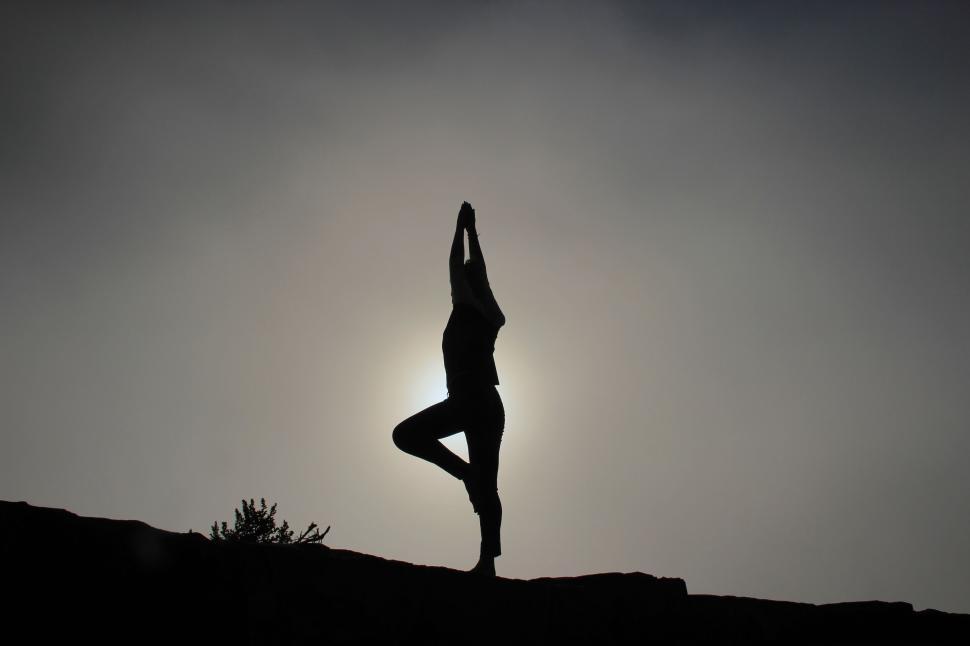 Free Image of Silhouette of person performing yoga pose against sun 