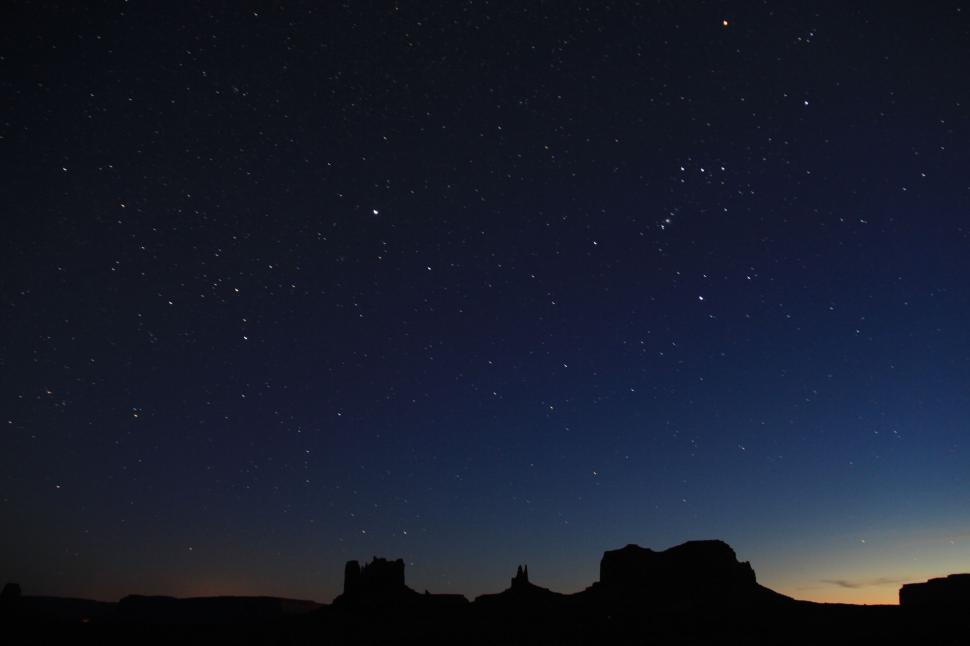 Free Image of Starry night sky over silhouettes of desert rocks 