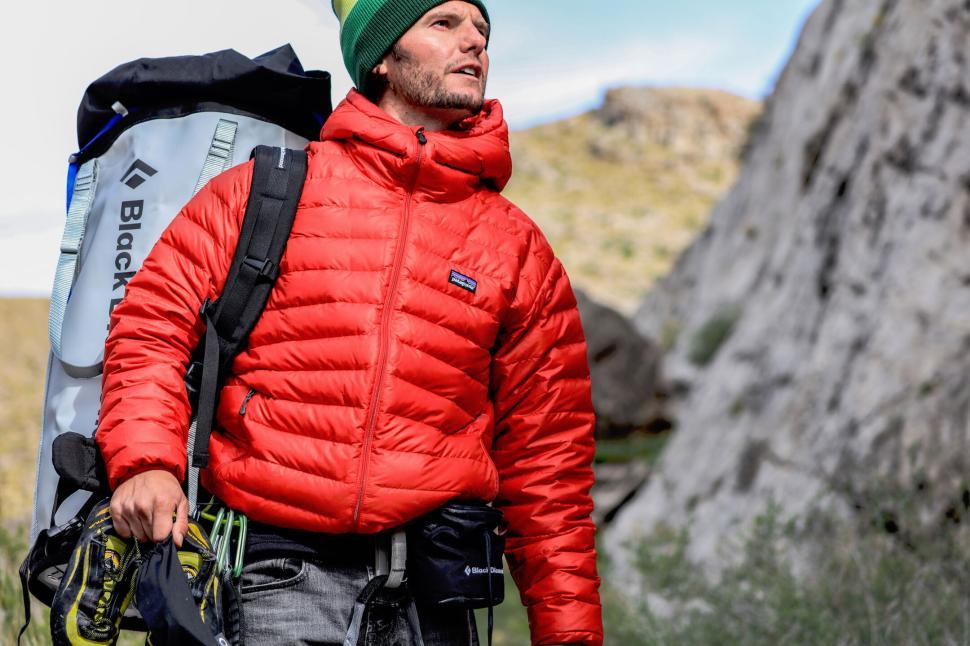 Free Image of Hiker in red jacket and green hat with climbing gear gear. 