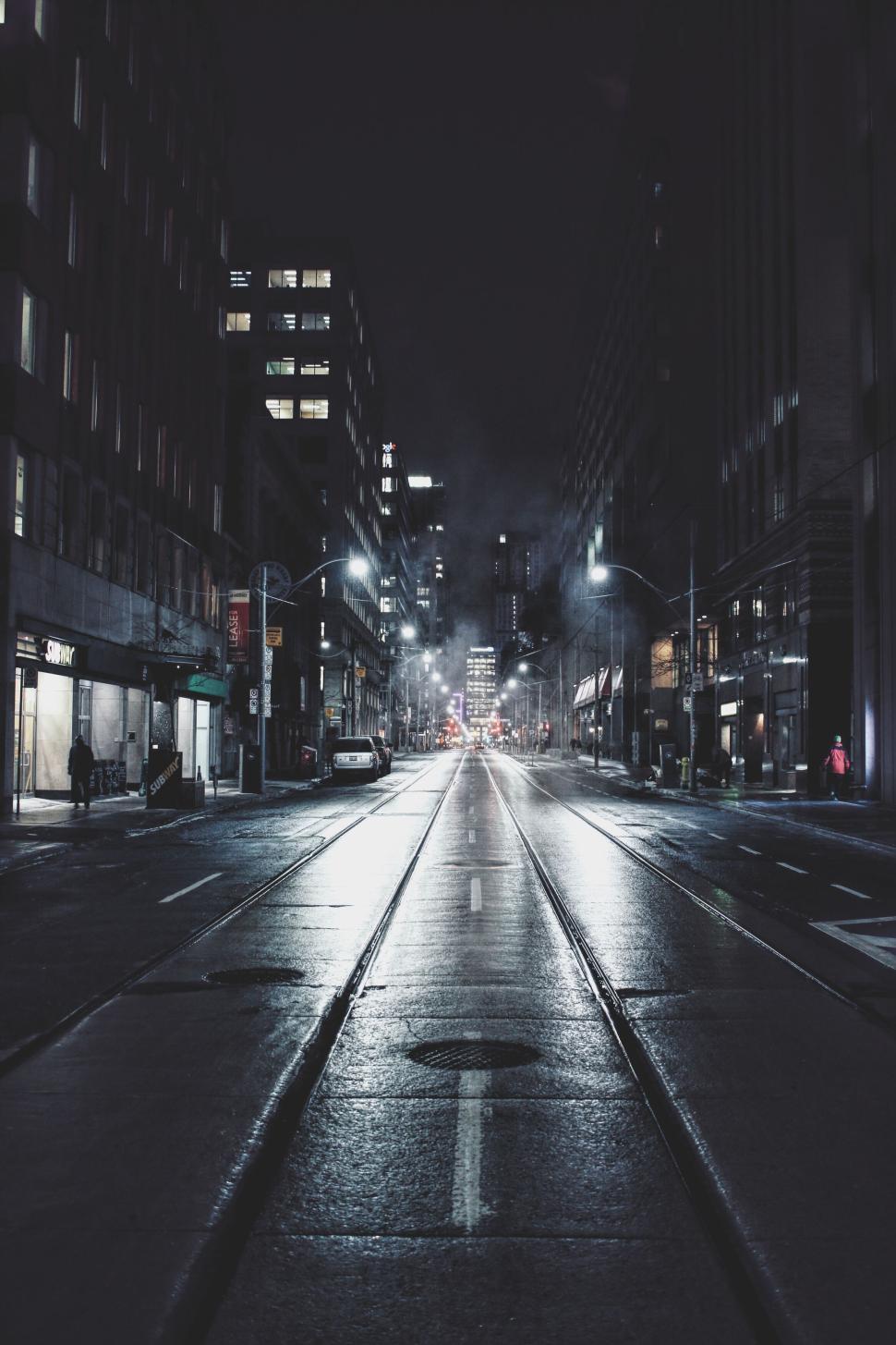 Free Image of Deserted city street at night with bright streetlights on. 