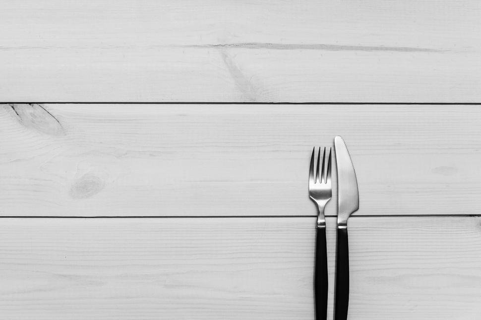 Free Image of Black-handled fork and knife placed neatly on table. 