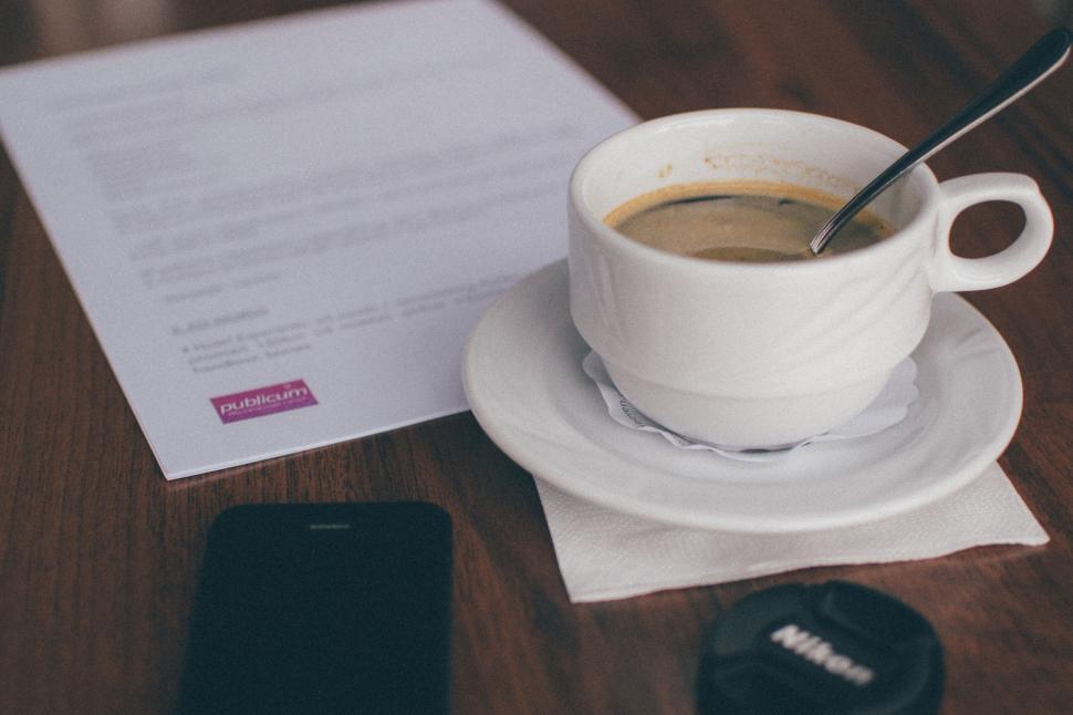 Free Image of Cup of coffee with documents and phone on table. 