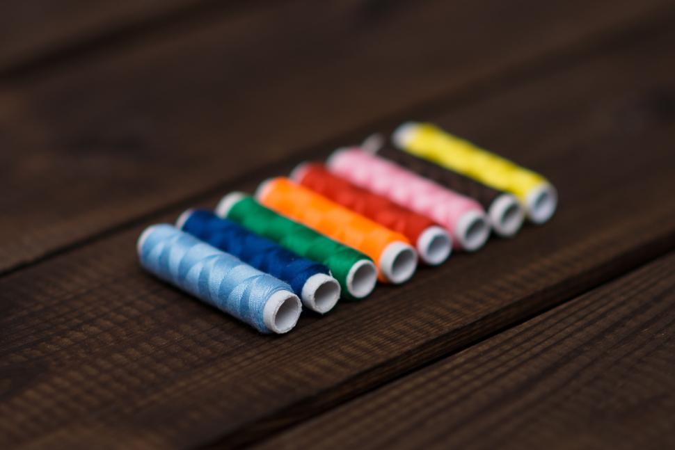Free Image of Set of colorful sewing threads on wooden background 