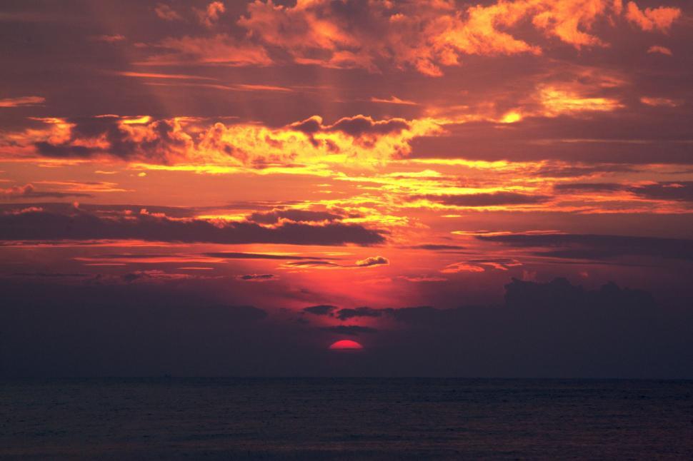 Free Image of A stunning sunset over a calm, vast ocean horizon. 