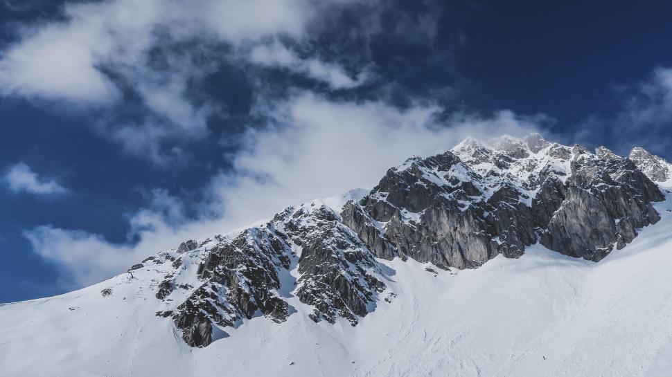 Free Image of Snow-covered mountain peaks under clear blue sky. 