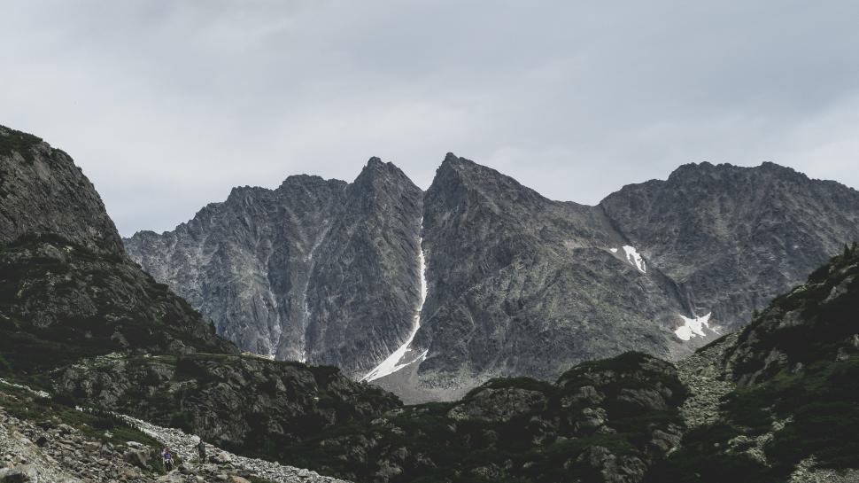 Free Image of Mountain range with rugged peaks and scattered snow patches 