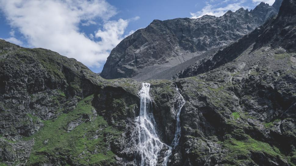 Free Image of Waterfall cascading down a rocky mountain in lush scenery 