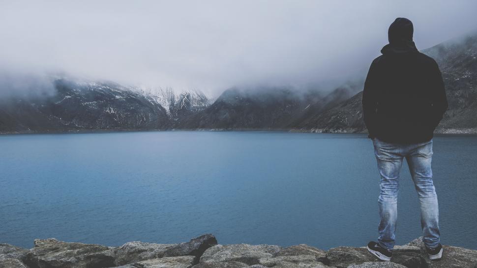 Free Image of Person looking over a serene lake with foggy mountains. 