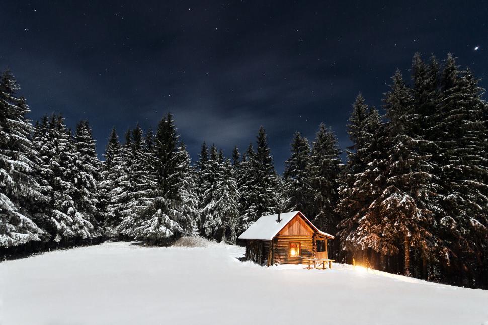 Free Image of A wooden cabin in a snowy forest under the stars. 