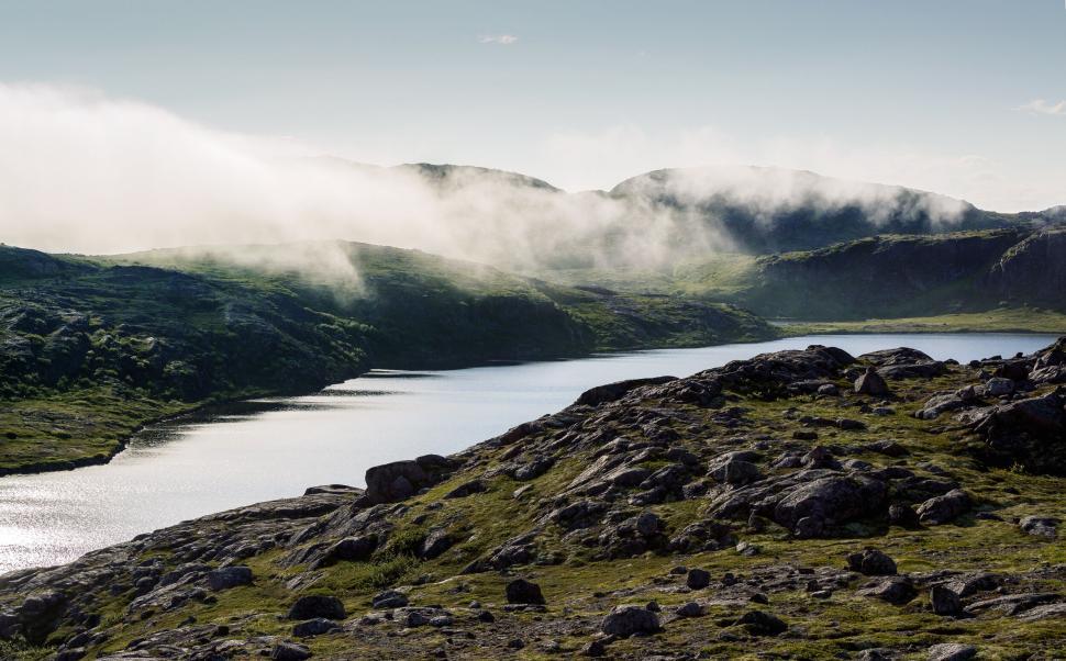 Free Image of A serene lake in a mountainous landscape with mist. 