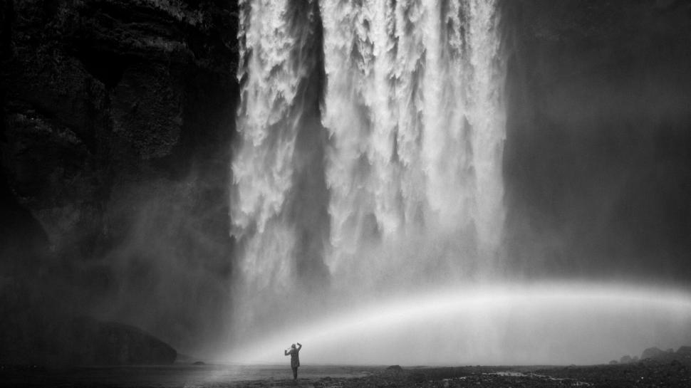 Free Image of A person standing in front of a large waterfall. 