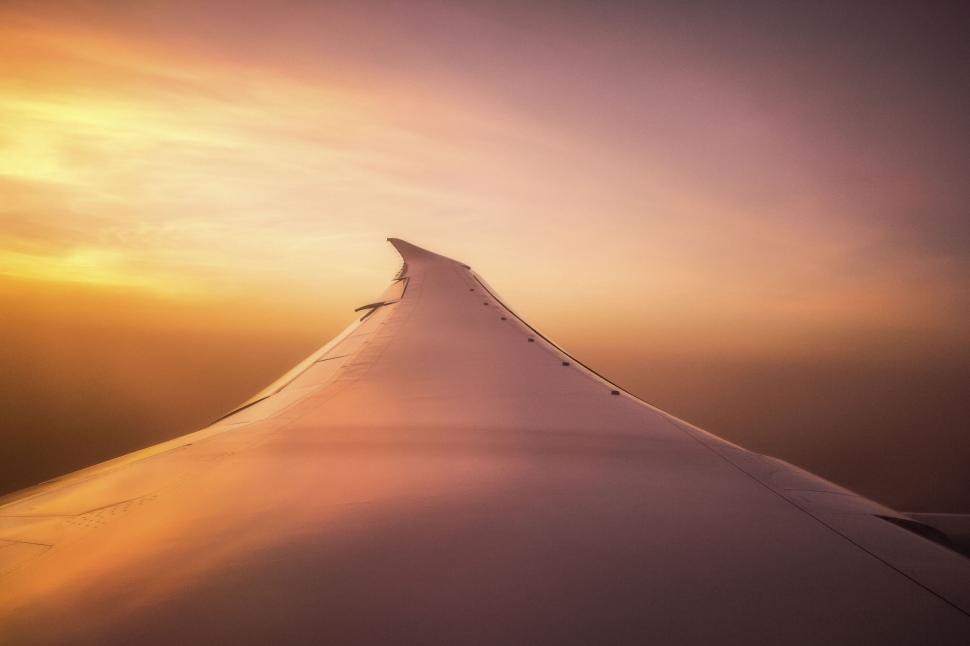 Free Image of Airplane wing during flight amidst a vibrant sunset 