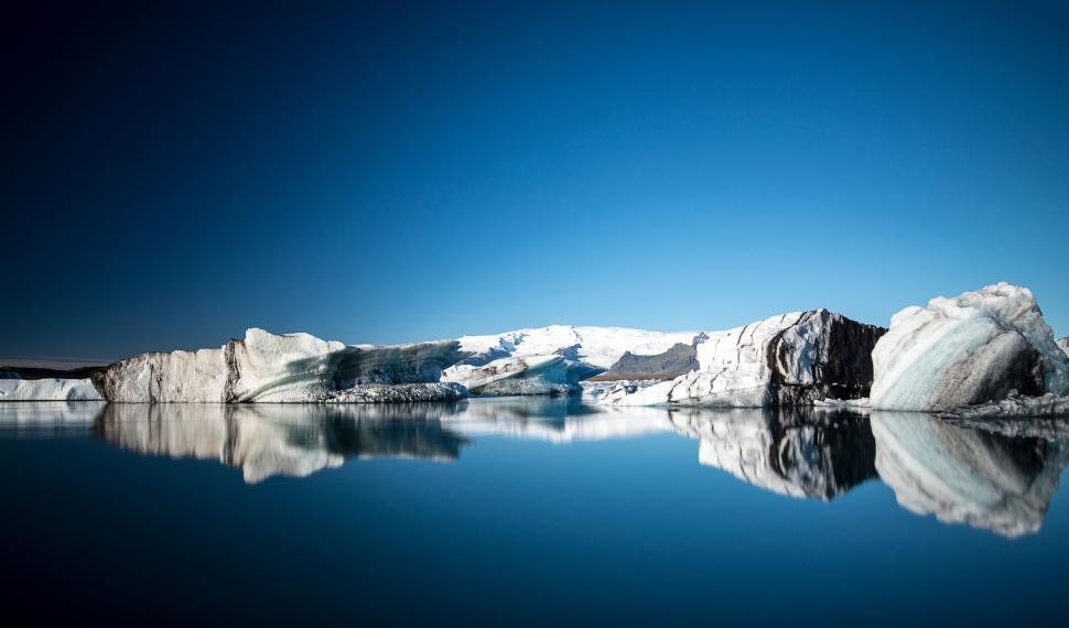 Free Image of Glistening glacier reflections on a calm icy lake surface. 