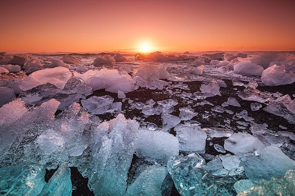 Free Image of Sunset over scattering ice on a rugged beach shore. 
