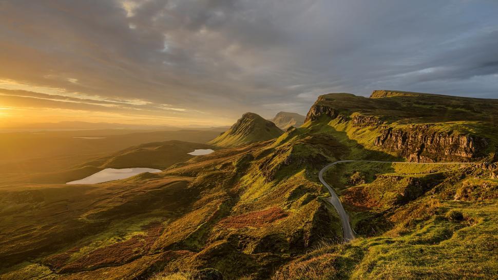 Free Image of Sunset over rolling hills with lakes and winding roads 