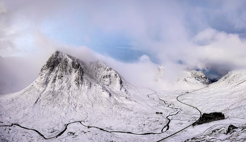 Free Image of Snow-covered mountains under a cloudy sky. 