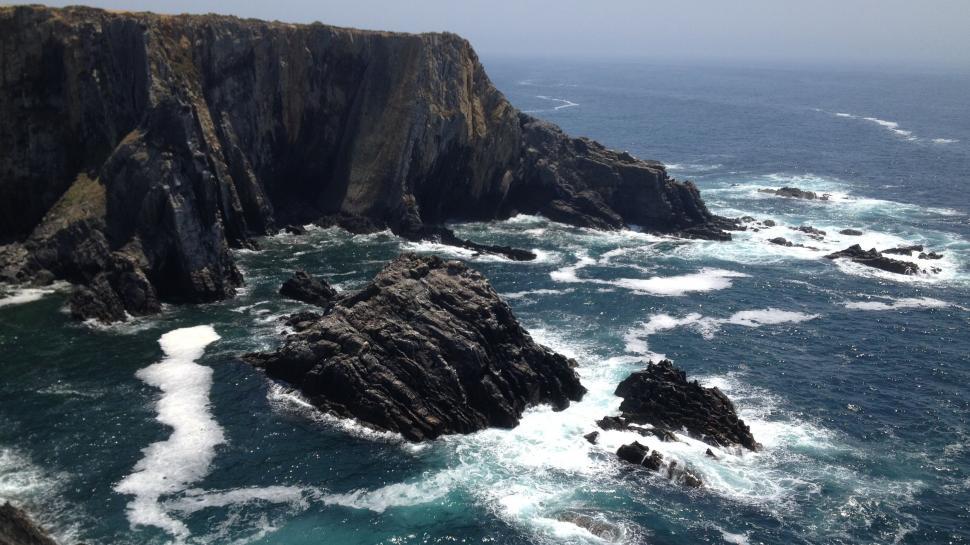 Free Image of Cliffside waves crashing against rocky coastal terrain 