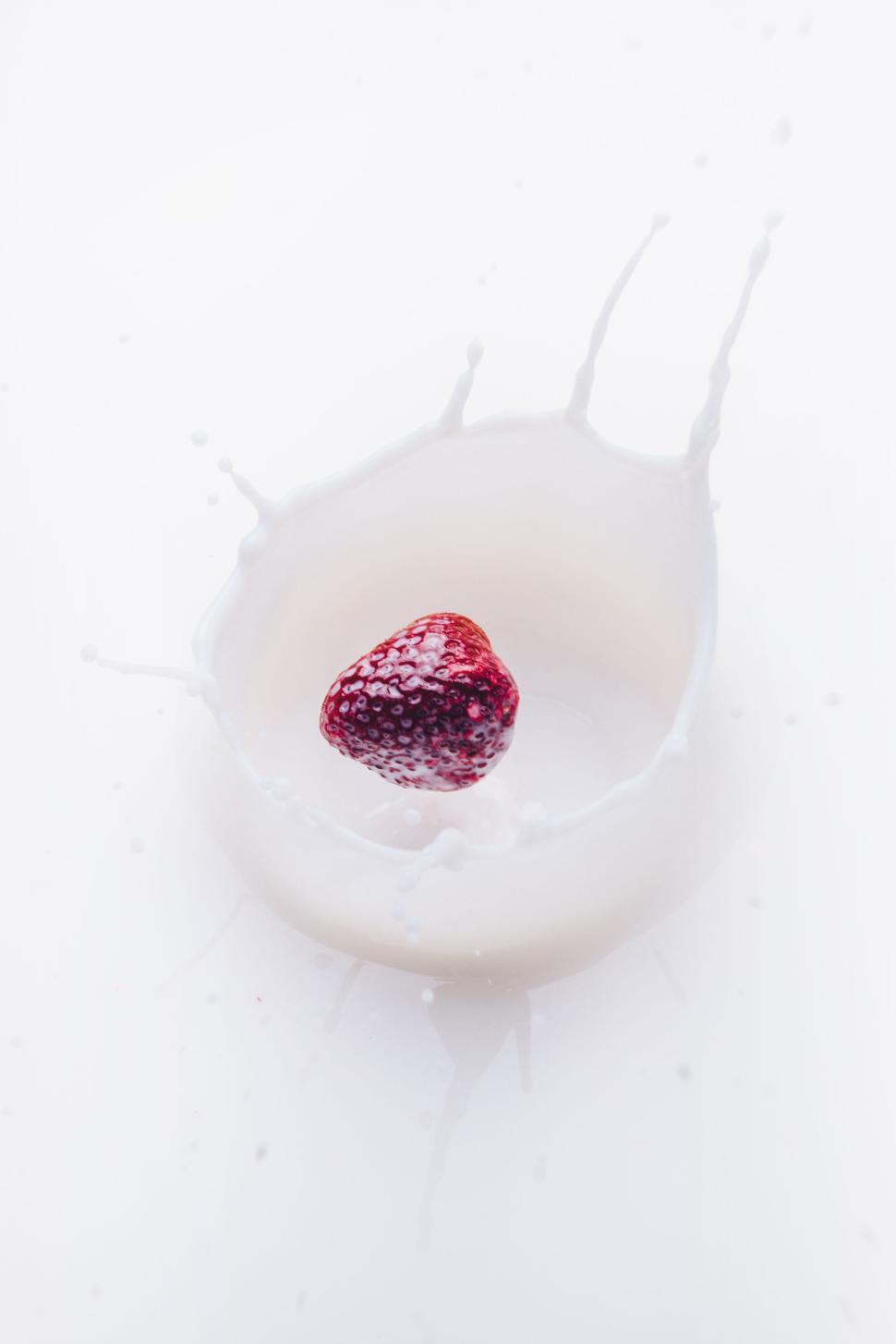 Free Image of Fresh strawberry splashing into milk creating a crown splash. 