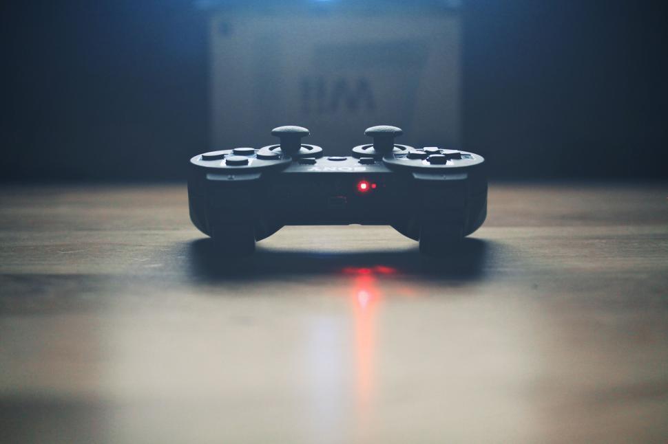 Free Image of Game controller on a wooden floor, red light glowing. 