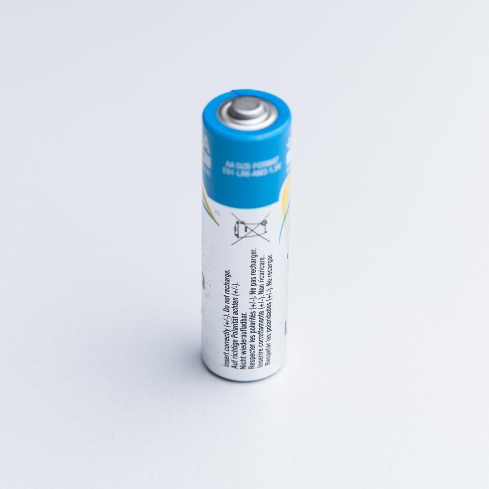 Free Image of Single AA battery standing upright against a light backdrop. 
