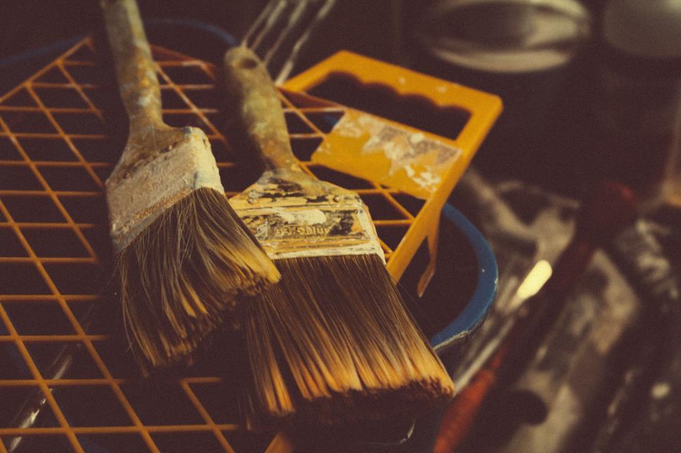 Free Image of Two old paintbrushes resting on a paint tray rack. 