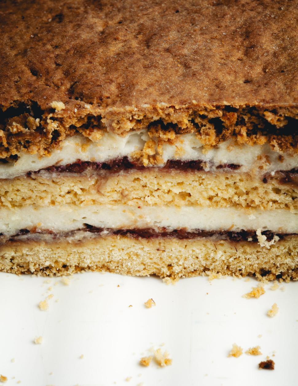 Free Image of Layered cream and jam cake with crumbled edges cut. 