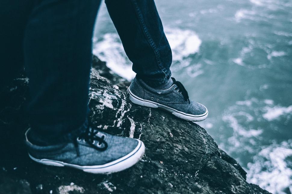 Free Image of Person standing on a rocky cliff by the ocean side. 