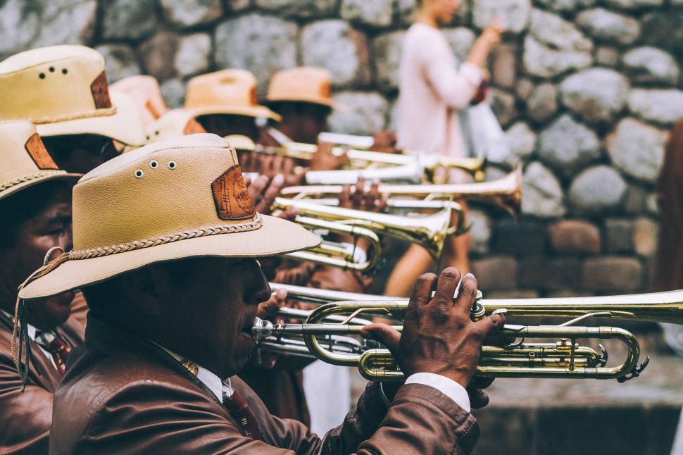 Free Image of A brass band performs in front of stone wall background. 