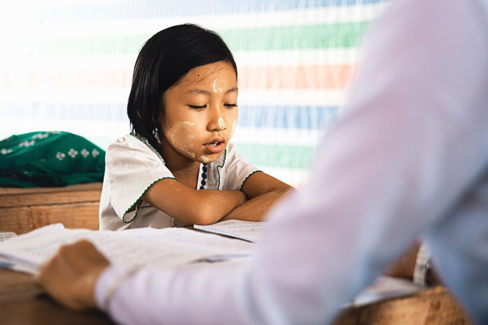 Free Image of Child with thanaka paste studying in a traditional room 