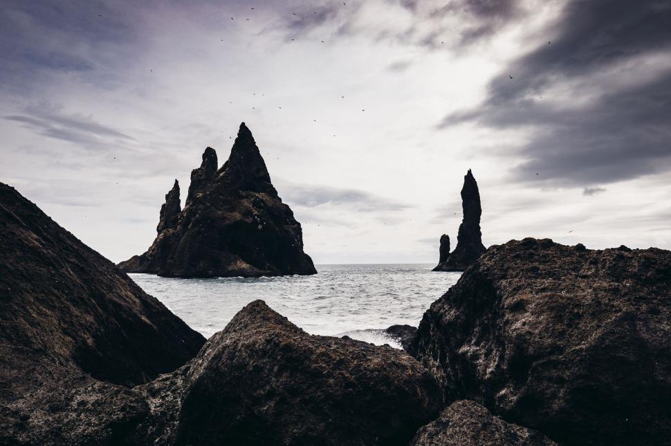 Free Image of Two towering rock formations in the sea under overcast sky 