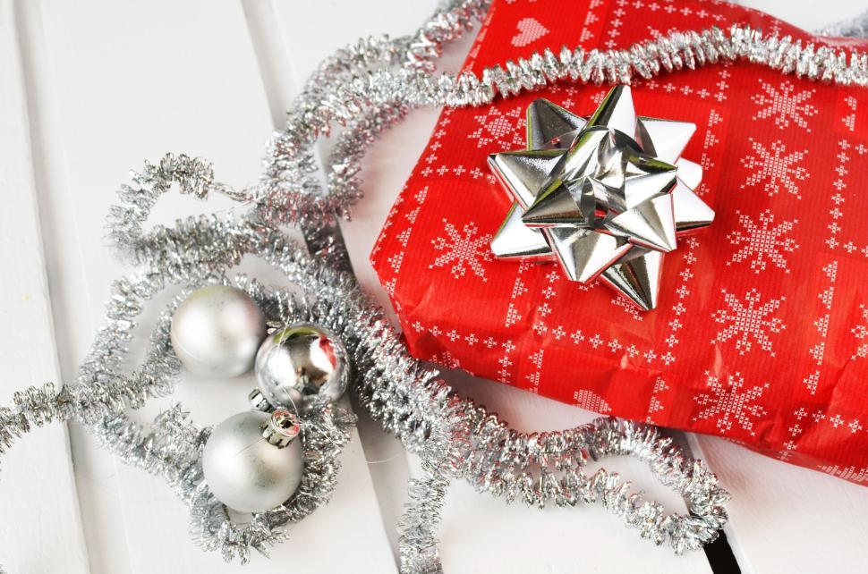 Free Image of Red Christmas gift with silver bow and decor elements. 