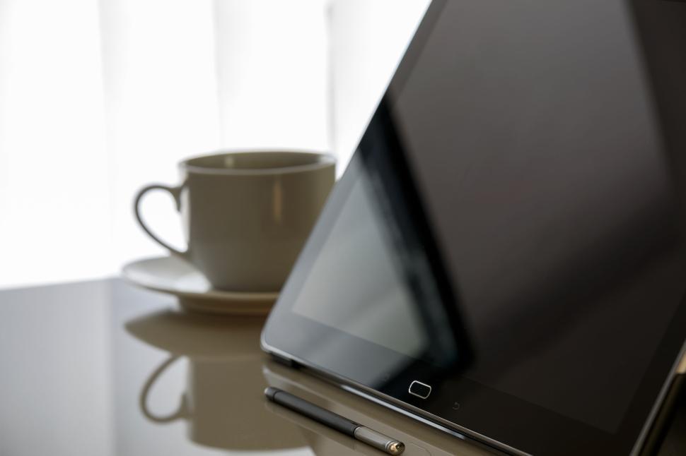Free Image of Tablet, stylus, and coffee cup on reflective table 