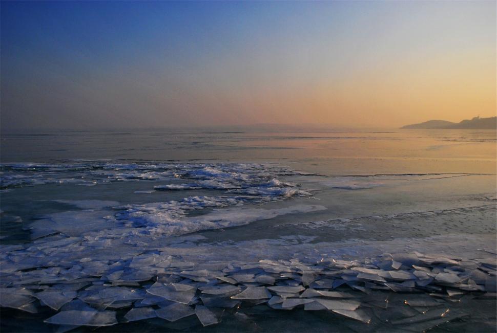 Free Image of Broken ice pieces floating on a calm, frozen lake surface. 