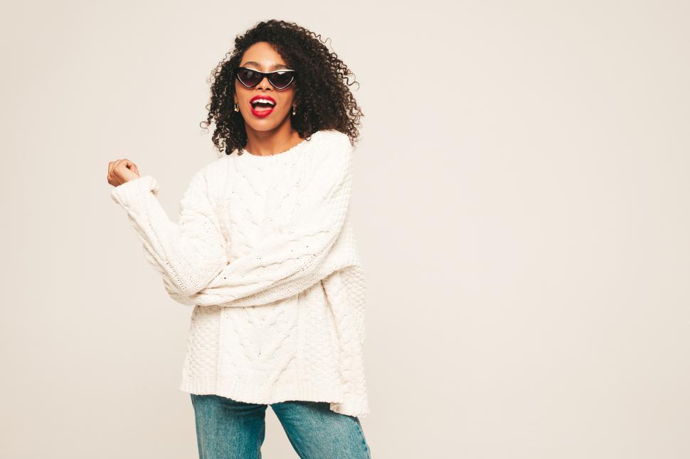 Free Image of Woman in white sweater and sunglasses, joyful pose 