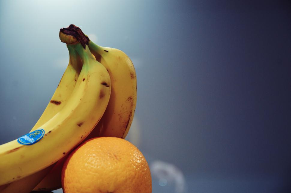 Free Image of Bunch of ripe bananas and a juicy orange fruit together. 