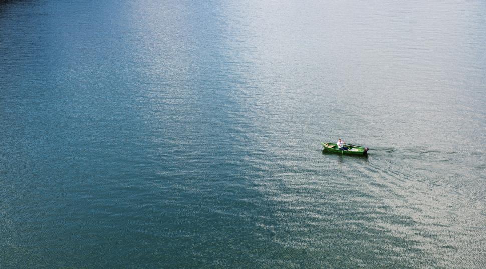 Free Image of Lone kayaker paddling across a calm, expansive lake 