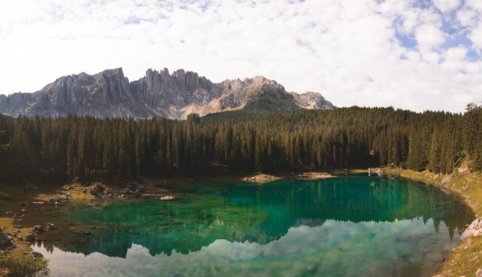Free Image of Clear green lake reflecting towering, rocky mountains. 