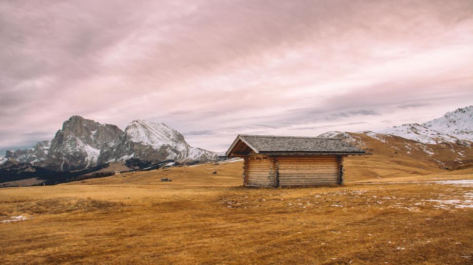 Free Image of Lonely cabin in autumn meadow with snowy mountains 